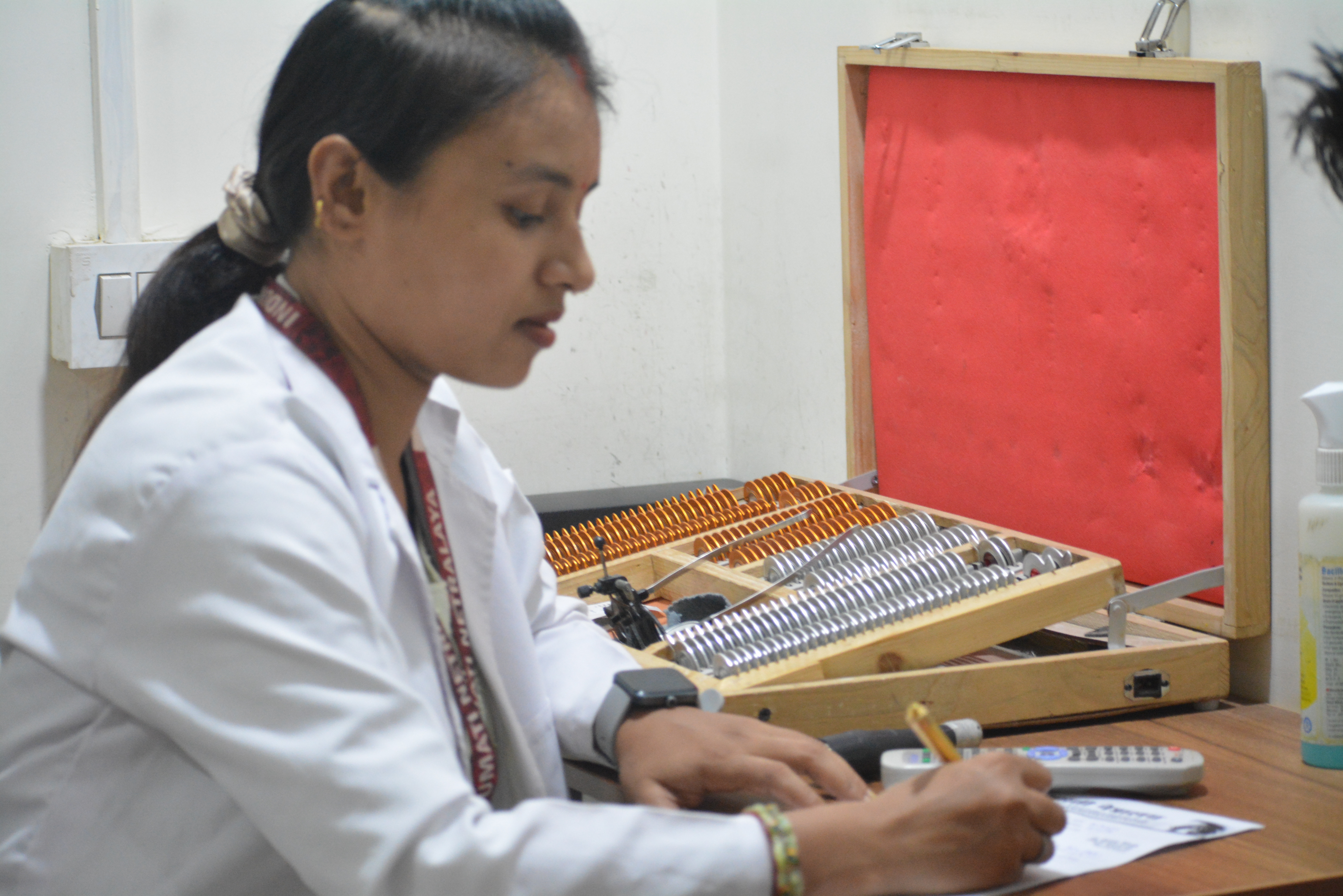 Optometrist performing refraction test with trial lens box at Indumati Netralaya